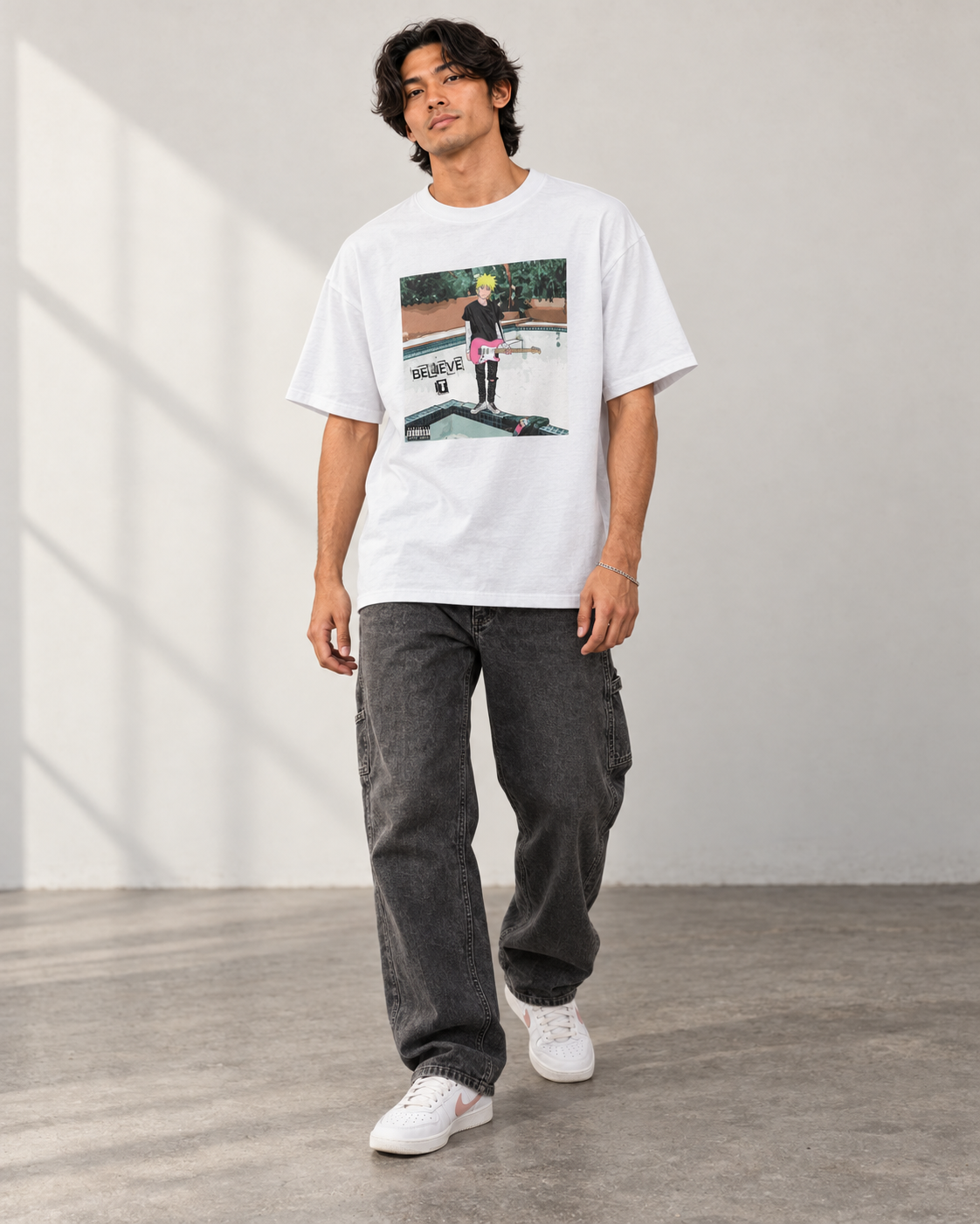 Model wearing the white Believe It Album Cover T-Shirt with charcoal carpenter jeans and white sneakers.