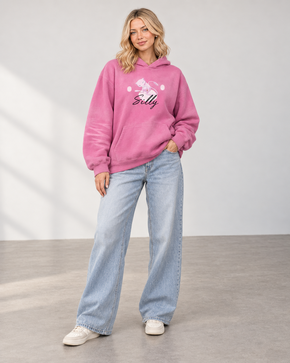 Model wearing the rose pink "Silly" Monkey hoodie with relaxed light denim and cream sneakers.
